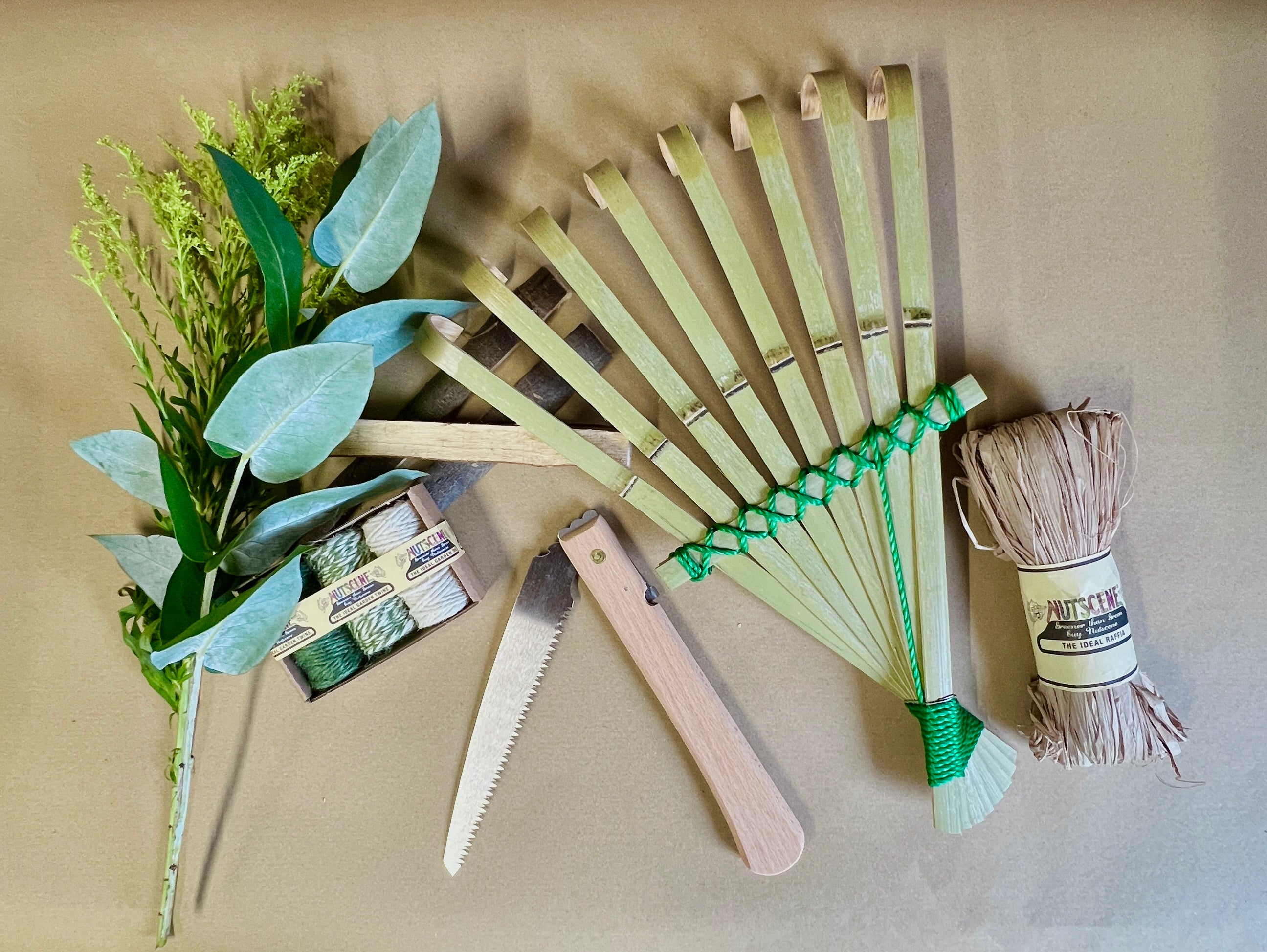 Set of gardening tools including a fan-shaped tool, shears, and twine on a beige background